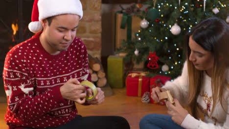 Rising-Shot-of-Young-Couple-Wrapping-Up-Christmas-Presents-Together