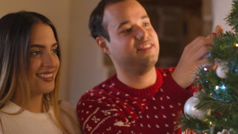 Close-Up-Shot-of-a-Joyful-Young-Couple-Decorating-Christmas-Tree-Together