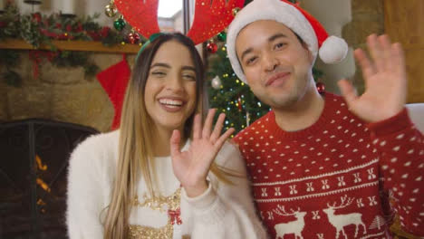Young-Couple-Waving-and-Talking-to-Camera-During-Christmas-Video-Call-