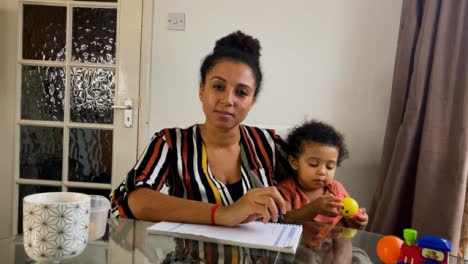 Young-Woman-with-Small-Child-On-Business-Video-Call-Listening-Intently-Whilst-Looking-Directly-to-Camera