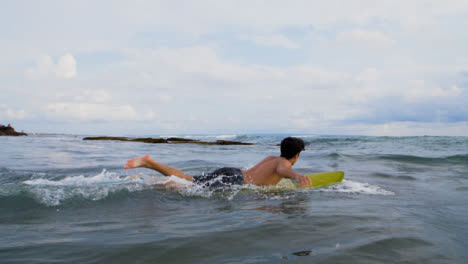 Handheld-Wide-Shot-of-Young-Surfer-Running-Into-Sea