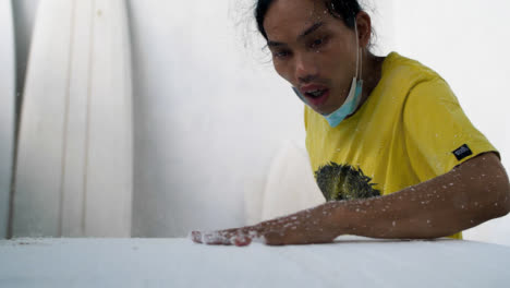 Handheld-Wide-Shot-of-Surboard-Shaper-Blowing-Away-Excess-Polystyrene