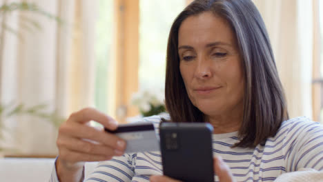 Close-Up-Shot-Revealing-Middle-Aged-Woman-Using-Smartphone-to-Make-Online-Purchase