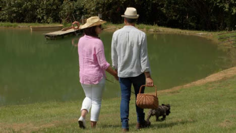 Tracking-Shot-Following-a-Middle-Aged-Couple-Walking-Dog-Next-to-Scenic-Lake