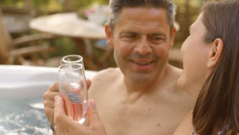 Tire-De-Disparo-De-Enfoque-De-Pareja-De-Mediana-Edad-Disfrutando-De-Champán-En-El-Jacuzzi