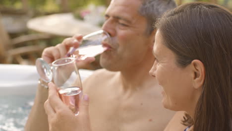 Pull-Focus-Shot-of-Middle-Aged-Couple-Enjoying-Champagne-In-Hot-Tub