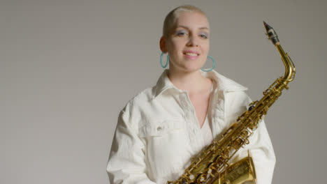 Portrait-Shot-of-Female-Model-Posing-and-Smiling-to-Camera-Whilst-Holding-Saxophone