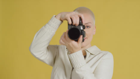 Weibliches-Kaukasisches-Modell-Posiert-Mit-Dslr-Vor-Gelbem-Hintergrund-05