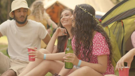Tracking-Shot-of-Young-Festival-Goers-Sitting-Around-Talking-and-Drinking