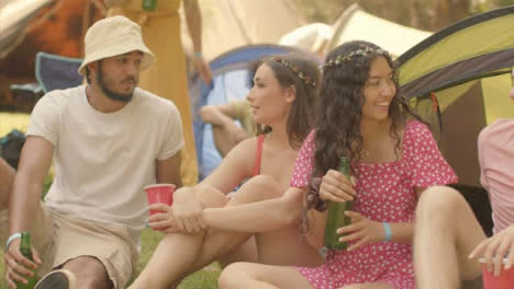 Tracking-Shot-of-Young-Festival-Goers-Sitting-Around-Drinking-and-Talking