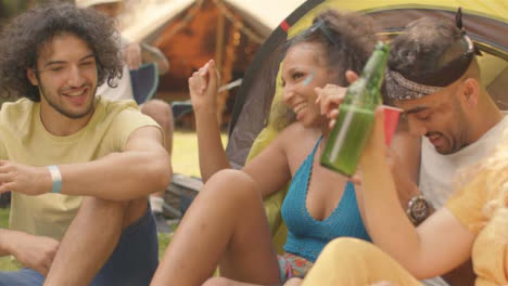 Tracking-Shot-of-Young-Festival-Goers-Sitting-with-One-Another-Talking-and-Drinking