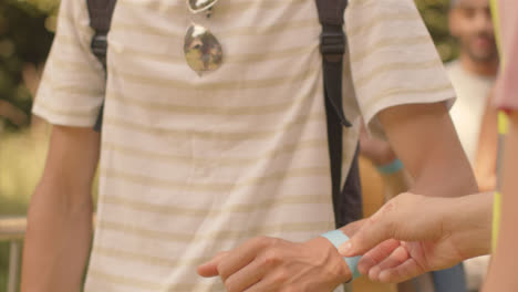 Close-Up-Shot-of-Festival-Goers-Showing-Wrist-Bands-to-Security-Guard