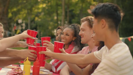 Tracking-Shot-Orbiting-Group-of-Friends-Sitting-Around-Table-Talking-and-Drinking