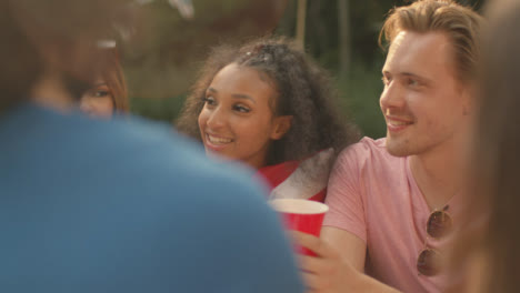 über-Die-Schulter-Geschossen-Von-Einer-Gruppe-Von-Freunden,-Die-Am-Tisch-Sitzen-Und-Reden-Und-Trinken