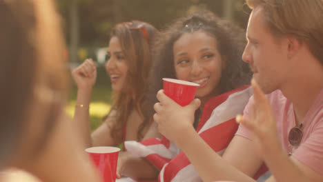 Over-the-Shoulder-Shot-of-Group-of-Friends-Sitting-Around-a-Table-Talking-and-Drinking