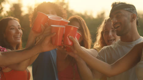 Medium-Shot-of-Group-of-Friends-Toasting-Their-Plastic-Beer-Cups-at-Sunset