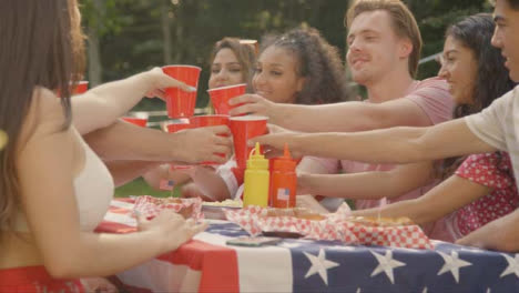 Plano-Deslizante-De-Un-Grupo-De-Amigos-Americanos-Sentados-Alrededor-De-Una-Mesa-Juntando-Sus-Bebidas