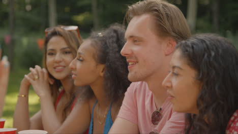 Over-the-Shoulder-Shot-of-Friends-Sitting-Around-Table-Drinking-and-Talking