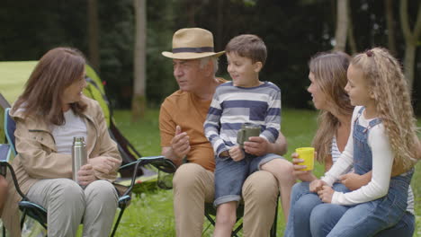 Kamerafahrt-Einer-Familie-Auf-Einem-Campingausflug,-Die-Neben-Ihren-Zelten-Sitzt-Und-Spricht-03