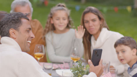 Over-the-Shoulder-Shot-of-Family-Taking-Selfie-at-Outdoor-Dinner-Table-02