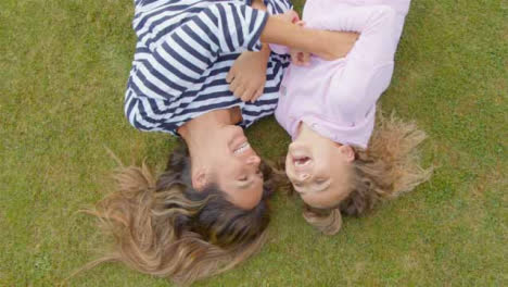 Top-Down-Shot-of-Mother-and-Daughter-Lying-On-Grass