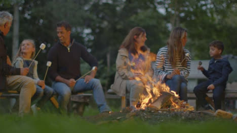 Low-Angle-Shot-of-Family-Sitting-Around-Campfire-Toast-Marshmallows