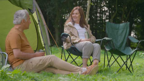 Low-Angle-Shot-of-Senior-Couple-Sitting-by-Their-Tents