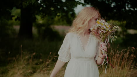 Attractive-Boho-Woman-Walking-On-A-Meadow-In-Summer-Holding-Flowers-In-Hand-1