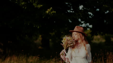Attractive-Boho-Woman-Walking-On-A-Meadow-In-Summer-Holding-Flowers-In-Hand-3
