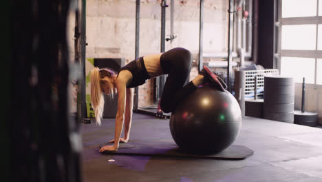 Side-View-Of-Young-Slim-Woman-Exercising-With-Stability-Ball-In-Gym