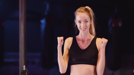 Portrait-Of-Attractive-Slim-Young-Woman-Cheering-With-Clenched-Fists-At-Fitness-Studio