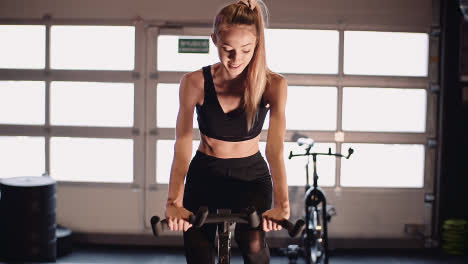 Determined-Young-Woman-Cycling-On-Stationary-Bike-At-Fitness-Studio-6