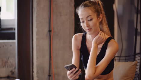 Lockdown-Shot-Of-Woman-Text-Messaging-Through-Smartphone-While-Relaxing-At-Health-Studio