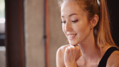 Beautiful-Female-Athlete-Text-Messaging-Through-Mobile-Phone-During-Break-At-Health-Studio-1