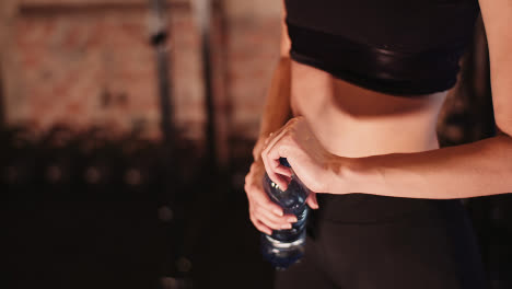 Midsection-Of-Young-Athletic-Woman-Holding-Water-Bottle-At-Fitness-Studio