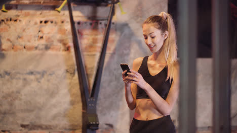 Beautiful-Young-Sporty-Woman-Using-Mobile-Phone-During-Break-At-Gym