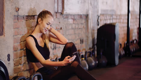 Schöne-Sportlerin-Textnachrichten-über-Handy-Während-Der-Pause-Im-Gesundheitsstudio-3