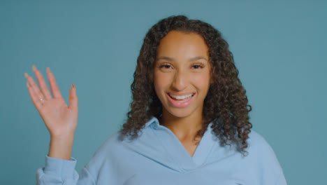 Portrait-Shot-of-Young-Adult-Woman-Smiling-and-Waving-to-Camera