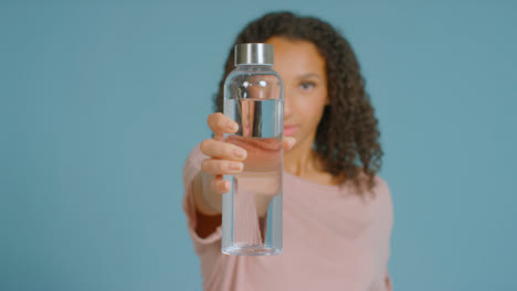 Portrait-Shot-of-Young-Adult-Woman-Drinking-Showing-Water-Bottle-to-Camera-02