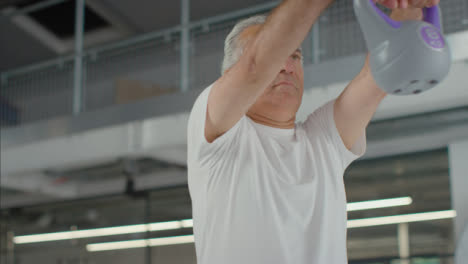 Flachwinkelaufnahme-Eines-älteren-Mannes,-Der-Mit-Wasserkochergewicht-Trainiert