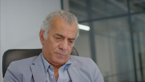 Close-Up-Shot-of-Senior-Man-Sitting-In-Computer-Chair-Looking-Down