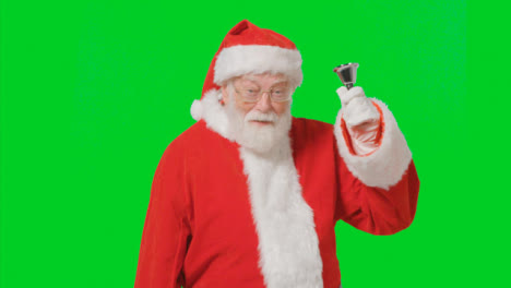 Portrait-Shot-of-Santa-Ringing-a-Bell-In-Front-of-a-Green-Screen