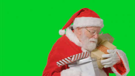 Portrait-Shot-of-Santa-Walking-Into-and-Out-of-Frame-Holding-Presents-with-a-Green-Screen