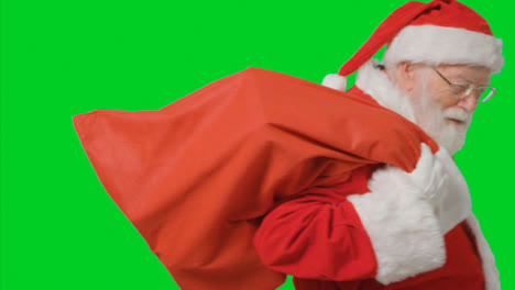 Portrait-Shot-of-Santa-Walking-Into-and-Out-of-Frame-Holding-Sack-with-Green-Screen