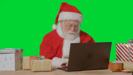 Portrait-Shot-of-Santa-Using-Laptop-In-Front-of-a-Green-Screen