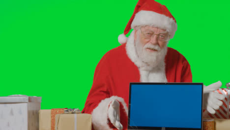Portrait-Shot-of-Santa-with-Blue-Screen-Laptop-In-Front-of-Green-Screen-