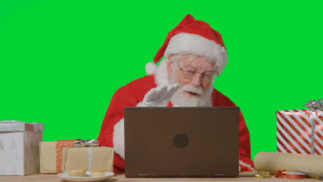 Portrait-Shot-of-Santa-Using-Laptop-for-Video-Call-In-Front-of-Green-Screen-