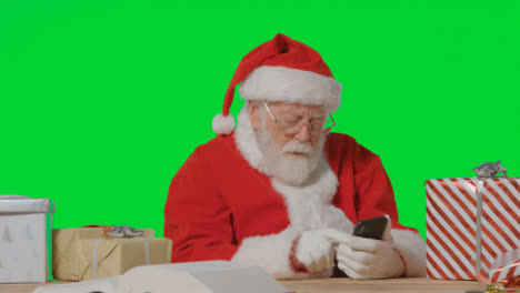 Portrait-Shot-of-Santa-Using-a-Mobile-Phone-In-Front-of-Green-Screen