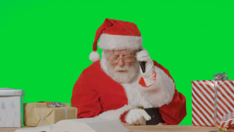 Portrait-Shot-of-Santa-Taking-a-Mobile-Phone-Call-In-Front-of-Green-Screen
