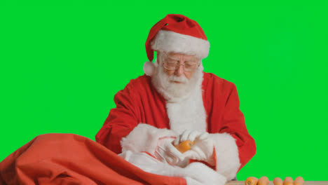 Portrait-Shot-of-Santa-Pulling-Carrots-Out-from-Sack-In-Front-of-Green-Screen-
